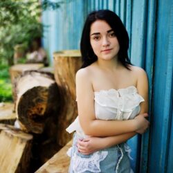 portrait-sexy-brunette-girl-women-s-jeans-shorts-white-blouse-against-blue-wooden-house-with-stumps (1) (1) (2)